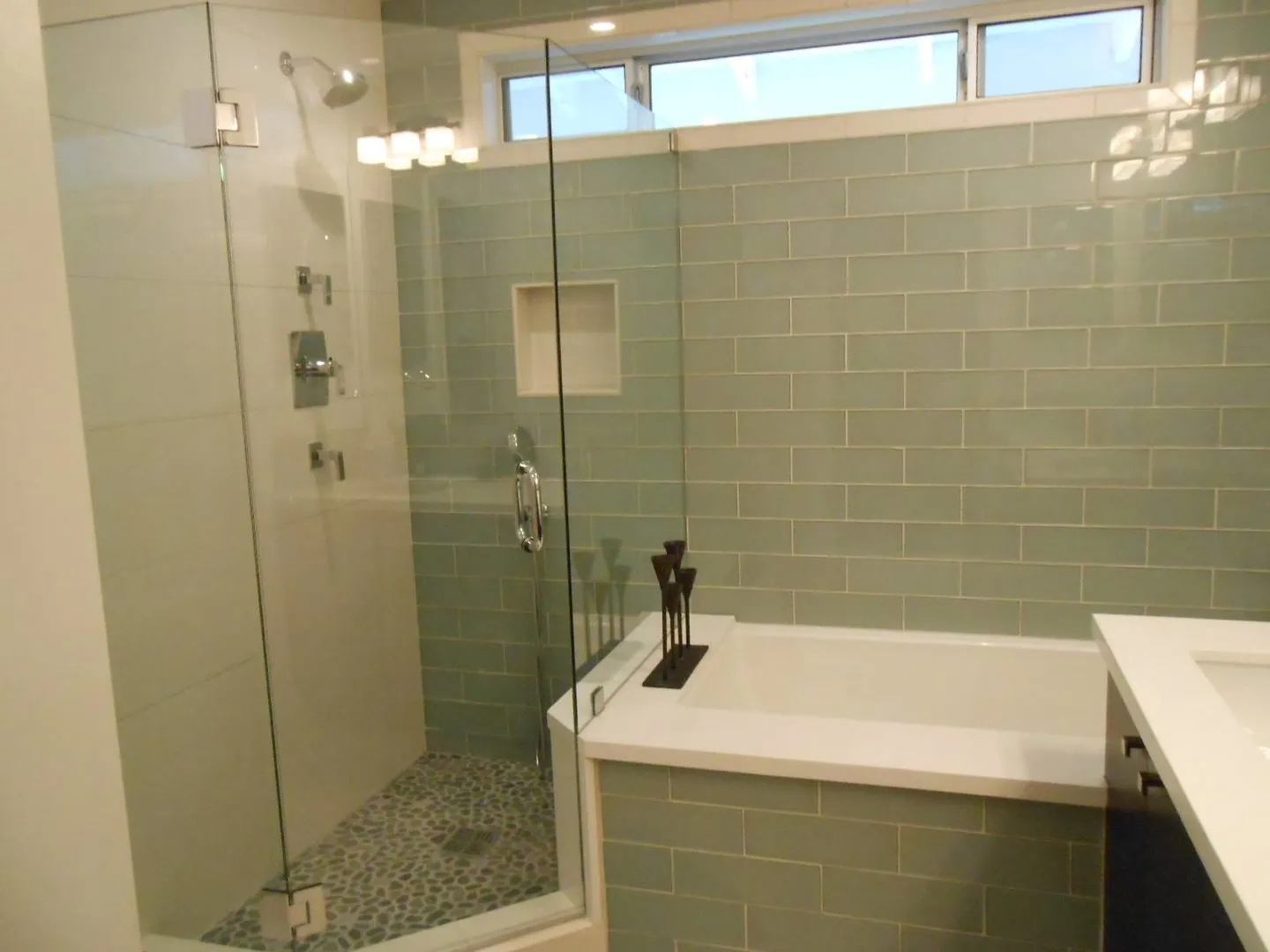 Renovated bathroom with green subway tile tub surround