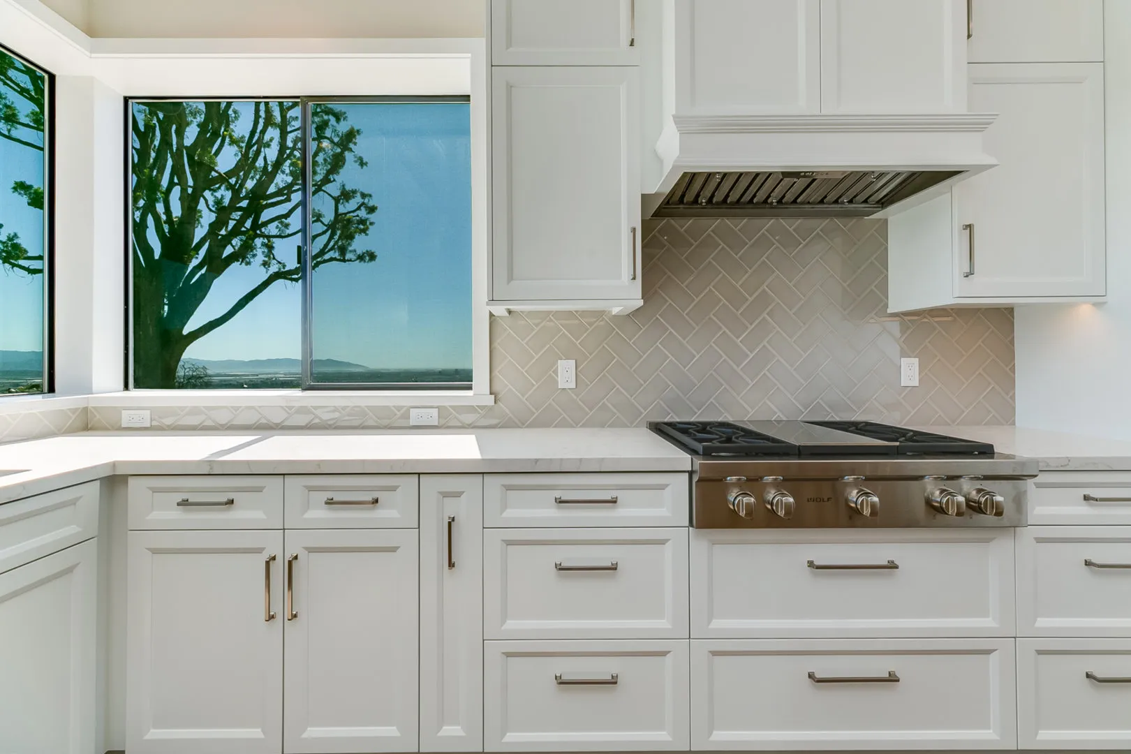 White kitchen with professional range and picture window