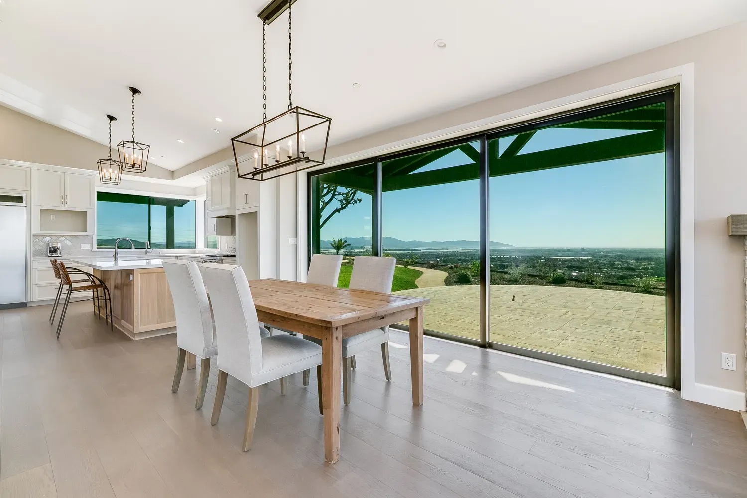 Dining area opening through sliding glass to the pergola and hills