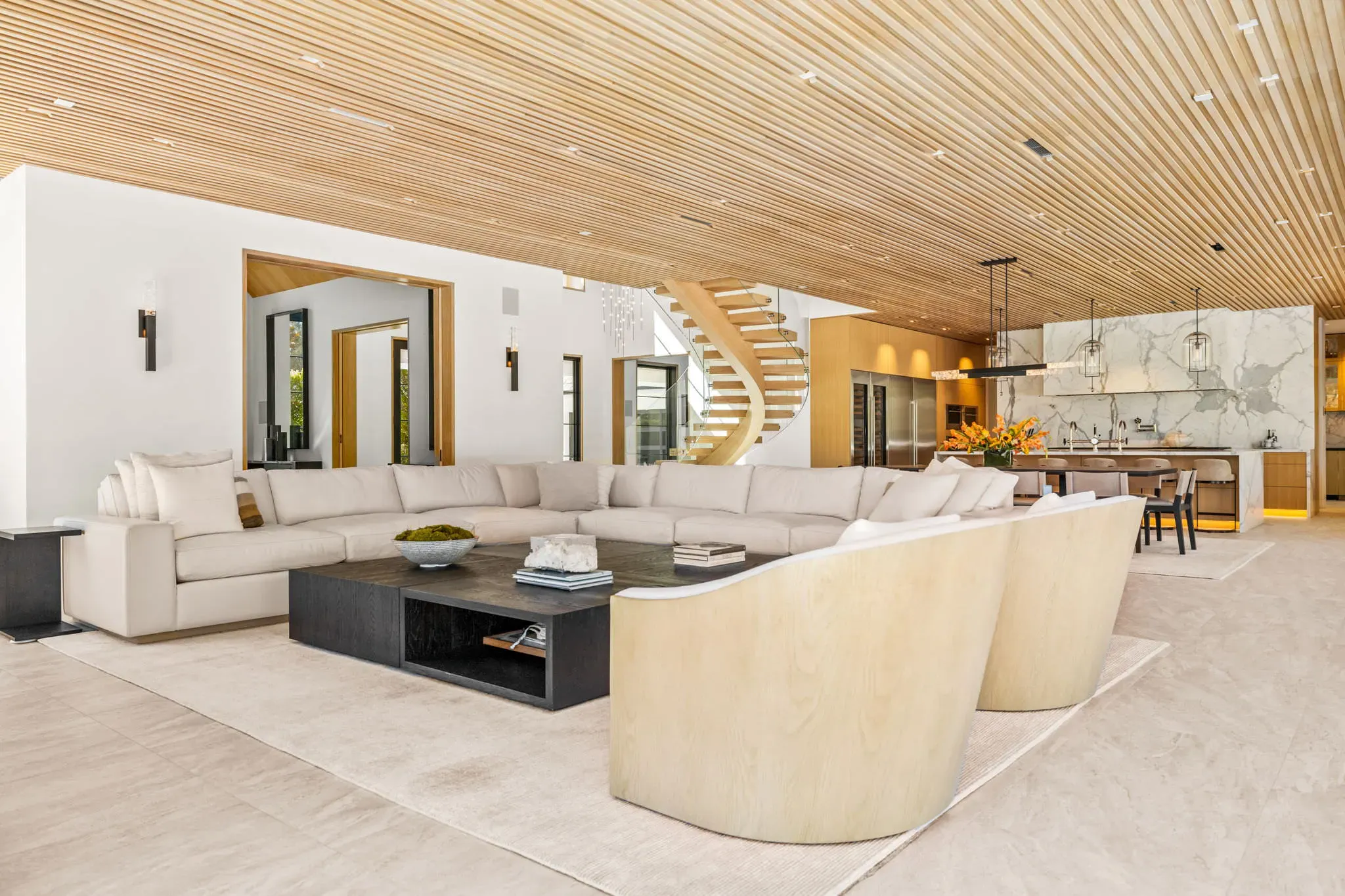 Great room opening to the kitchen with curved staircase beyond